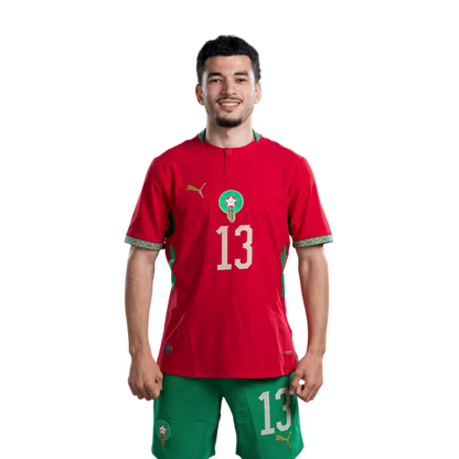 قميص المنتخب المغربي لكرة القدم لكأس العالم 2026 (نسخة اللاعبين/نسخة المباريات) — المدافعون: رقم 13 زكريا الواحدي، رقم 14 عيسى ديوب، رقم 18 شادي رياض.