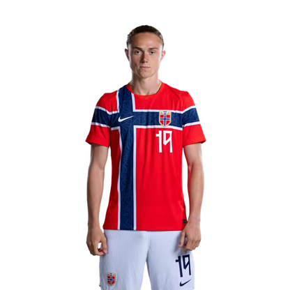 Norges fotballag 2026 VM-drakt (spillerversjon/kampversjon) — Midtbanespillere: nr.19 Thelo AASGAARD, nr.21 Andreas SCHJELDERUP, nr.22 Oscar BOBB, nr.23 Jens Petter HAUGE